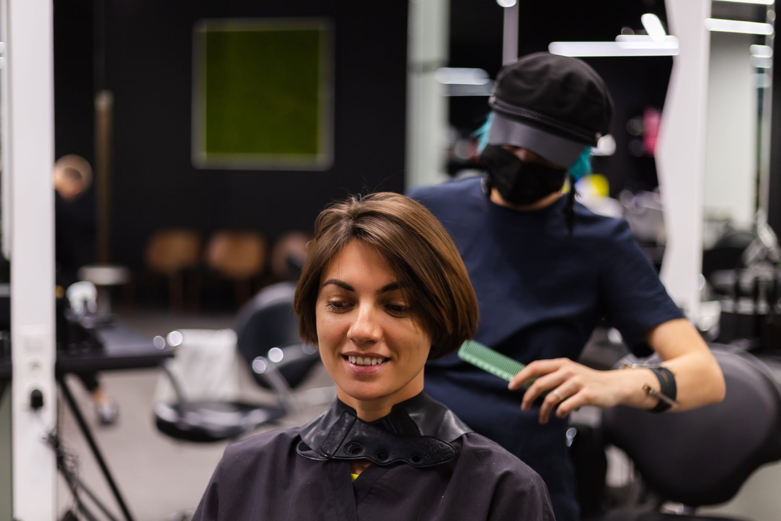 A professional girl hairdresser makes a client haircut. The girl is sitting in a mask in beauty the salon